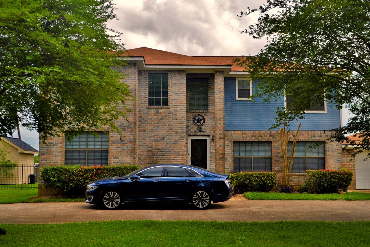 Auto insurance in Humble TX, with car parked outside brick home